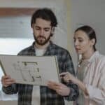 A man and woman examining a floor plan for home improvement indoors.